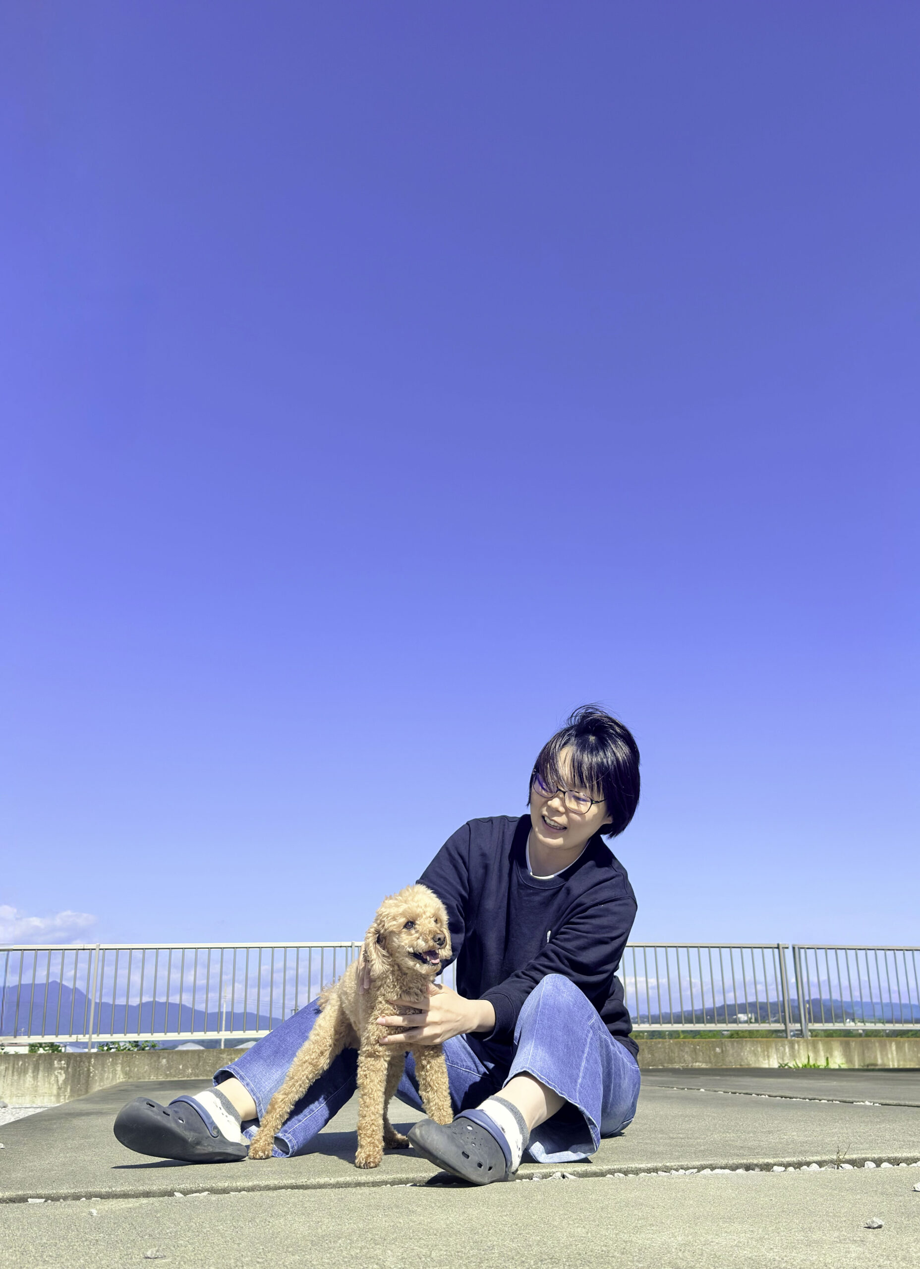 黒のトレーナーを着たショート髪の女性と茶毛のトイプードル